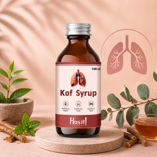 A 100 ml bottle of Hasit! Cough Syrup centered on a round wooden coaster, surrounded by herbal props including mint, cinnamon sticks, a small plant, and a glass of amber liquid, against a soft peach background with a stylized lungs graphic.
