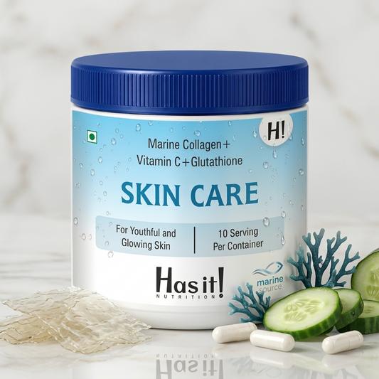 A white plastic supplement jar with a blue screw-top lid labeled 'SKIN CARE' by Hasit Nutrition, styled on a light marble surface with cucumber slices, capsules, and gel pieces around it.